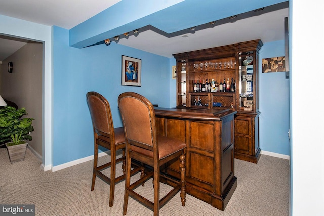 bar featuring a dry bar, baseboards, and light carpet