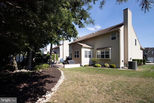 rear view of property featuring central air condition unit, a lawn, and a patio area