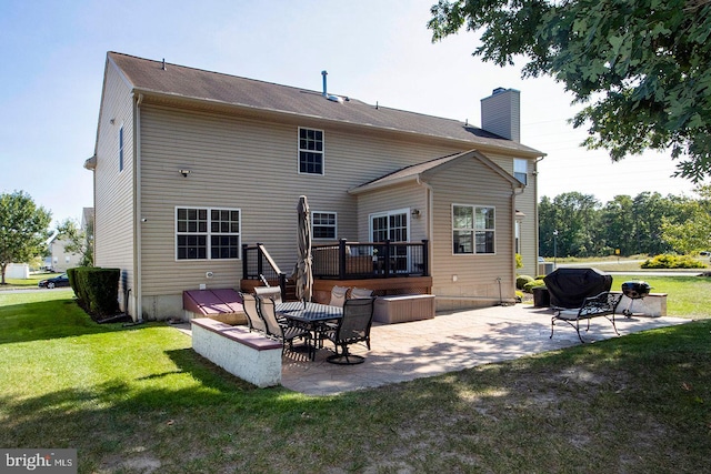 back of house featuring a deck, a patio, a yard, and a chimney