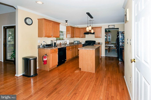 kitchen featuring black appliances, a sink, under cabinet range hood, wood finished floors, and crown molding