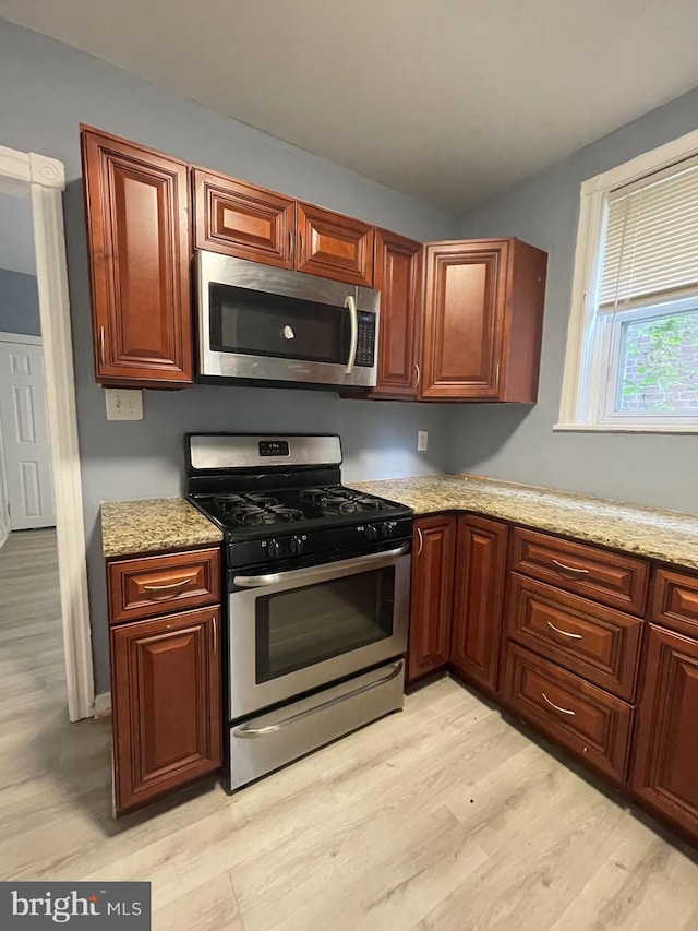 kitchen featuring appliances with stainless steel finishes, light stone countertops, and light hardwood / wood-style floors