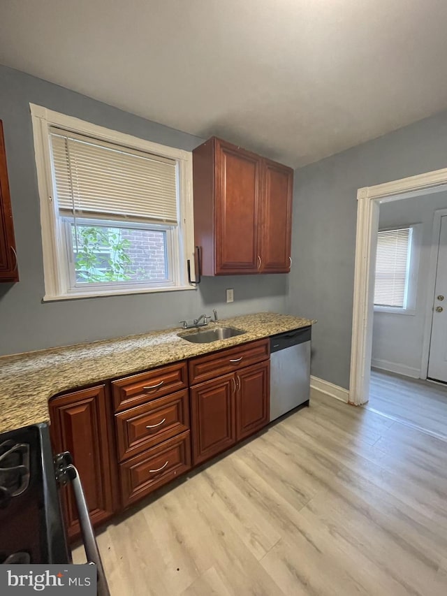 kitchen with light wood-type flooring, light stone countertops, sink, stove, and stainless steel dishwasher