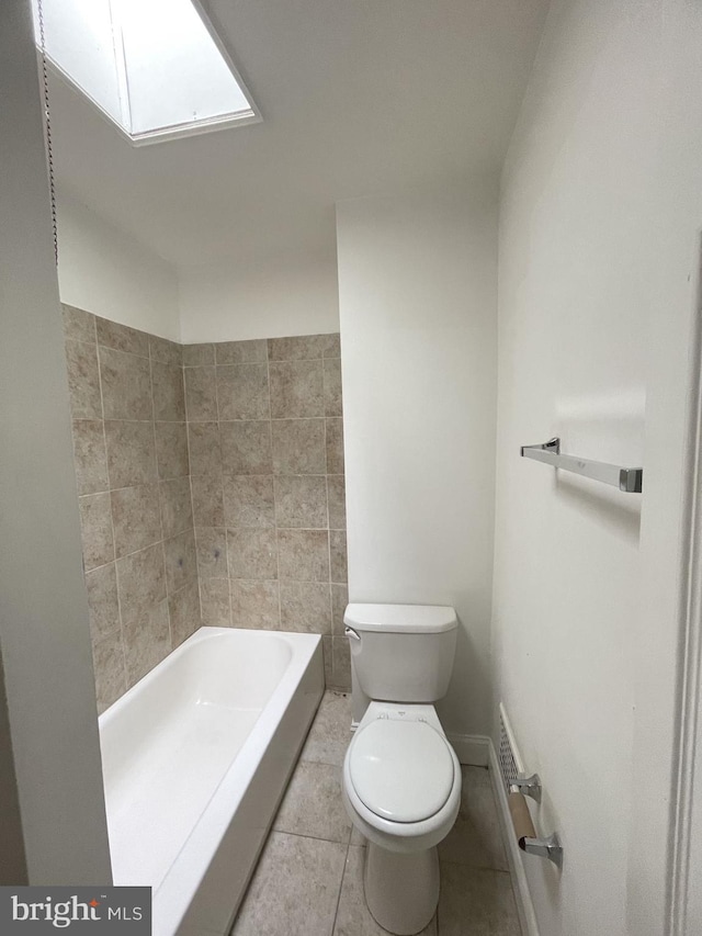 bathroom featuring a bath, a skylight, toilet, and tile patterned floors