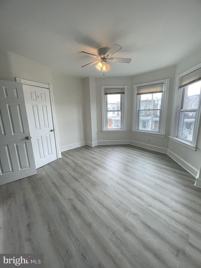 unfurnished bedroom featuring multiple windows, hardwood / wood-style floors, and ceiling fan