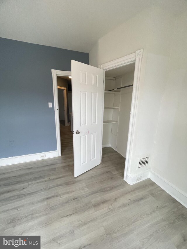 unfurnished bedroom with light hardwood / wood-style flooring and a closet