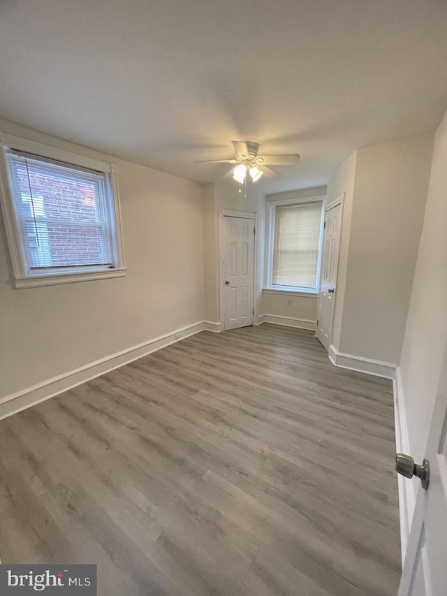 unfurnished bedroom with ceiling fan, wood-type flooring, and multiple windows