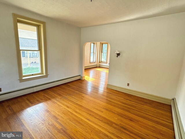 unfurnished room with light wood-type flooring, a textured ceiling, and baseboard heating