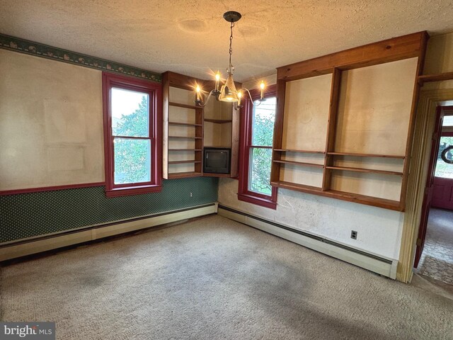 spare room featuring a notable chandelier, baseboard heating, carpet, and a textured ceiling