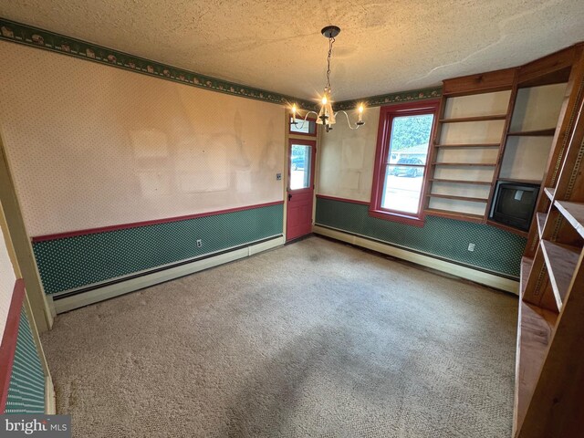 carpeted empty room with a baseboard heating unit, an inviting chandelier, and a textured ceiling