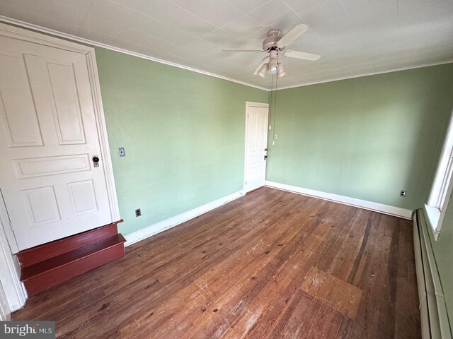 unfurnished bedroom featuring a baseboard radiator, ornamental molding, ceiling fan, and dark wood-type flooring