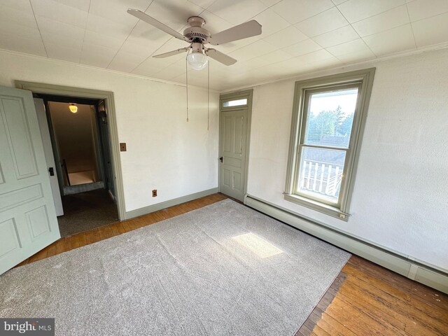 spare room featuring ceiling fan, ornamental molding, baseboard heating, and dark hardwood / wood-style flooring