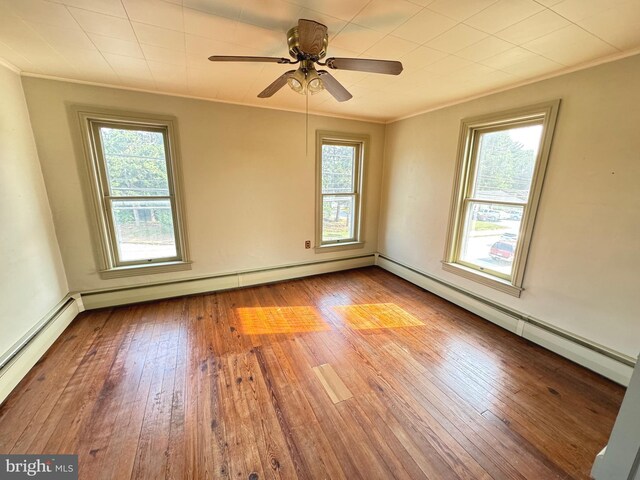 unfurnished bedroom with a baseboard heating unit, wood-type flooring, and crown molding