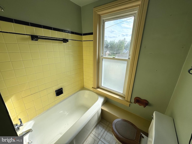 bathroom with a tub to relax in and toilet