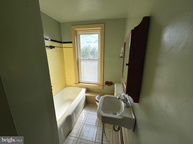 bathroom with toilet, a washtub, and sink