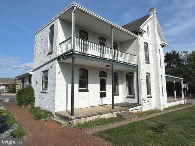 view of front of property with a balcony and a front lawn