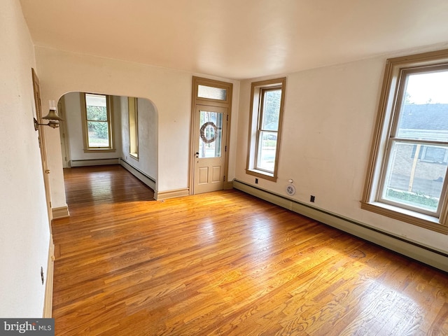 foyer entrance featuring a baseboard heating unit, light wood-type flooring, and plenty of natural light