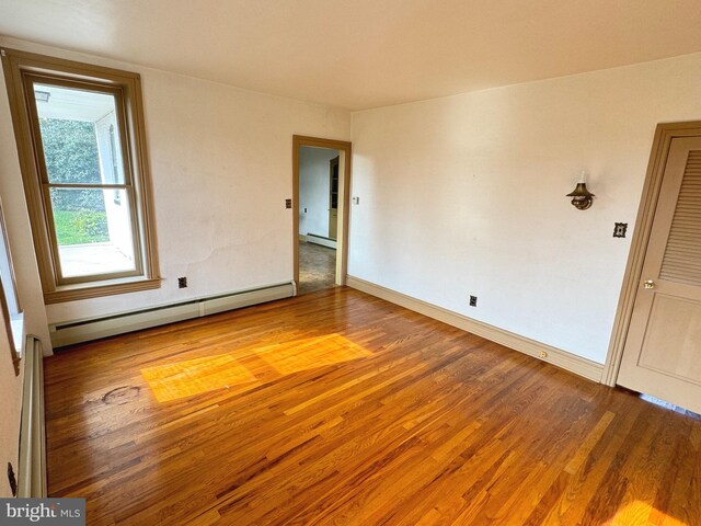 spare room featuring baseboard heating and hardwood / wood-style floors