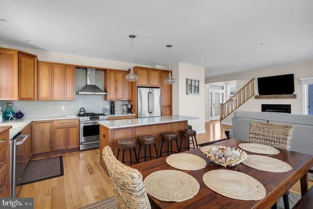 kitchen with a kitchen island, decorative light fixtures, stainless steel gas range oven, light hardwood / wood-style floors, and sink