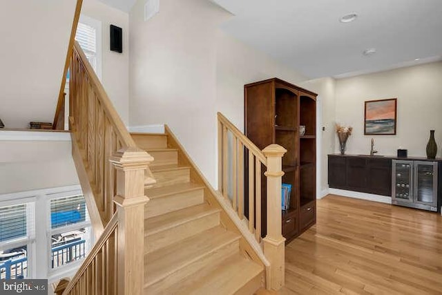 staircase with hardwood / wood-style floors and wine cooler