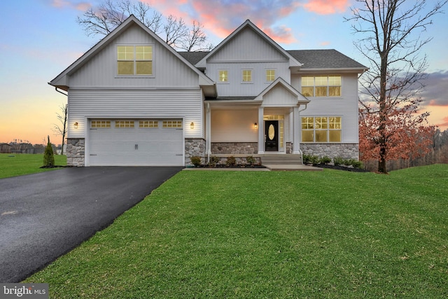 craftsman house featuring a front yard, roof with shingles, an attached garage, stone siding, and aphalt driveway