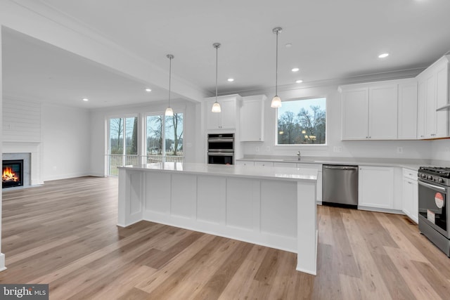 kitchen with white cabinets, appliances with stainless steel finishes, a center island, and a healthy amount of sunlight