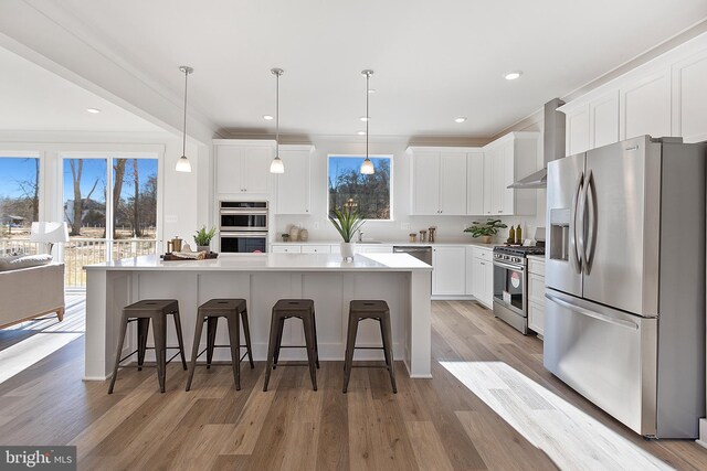 1333 German Driveway, Hanover, MD 21076 - kitchen with appliances with stainless steel finishes, wall chimney exhaust hood, a breakfast bar area, white cabinetry, and recessed lighting