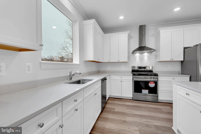 kitchen with a sink, stainless steel appliances, wall chimney exhaust hood, and white cabinets