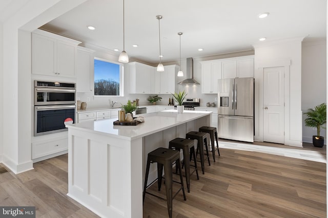 1333 German Driveway, Hanover, MD 21076 - kitchen with appliances with stainless steel finishes, wall chimney range hood, a kitchen island, white cabinets, and a kitchen bar