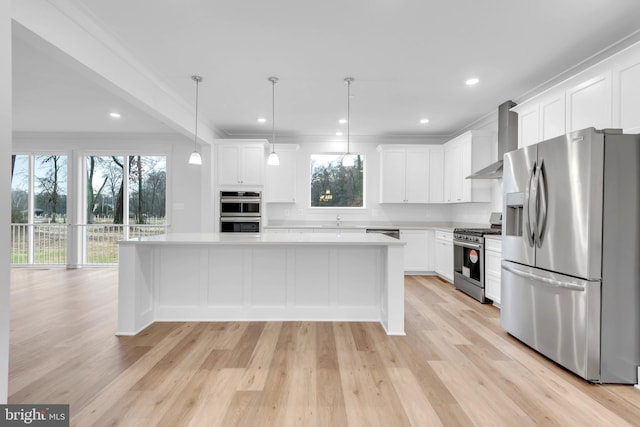 kitchen with a center island, white cabinets, wall chimney range hood, hanging light fixtures, and appliances with stainless steel finishes