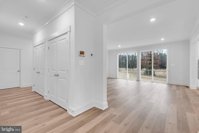 hall with baseboards, light wood-style floors, and ornamental molding