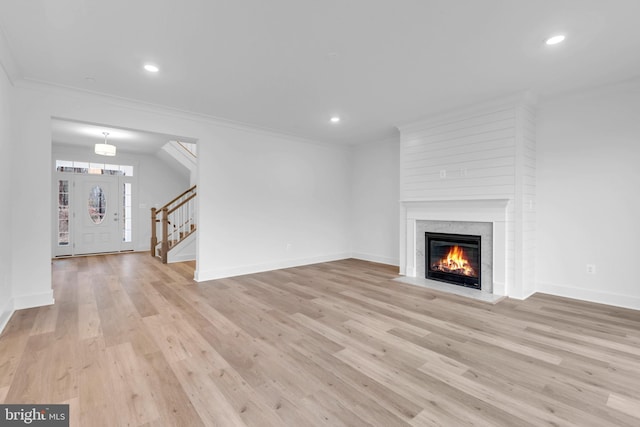 unfurnished living room featuring stairway, baseboards, light wood finished floors, recessed lighting, and ornamental molding