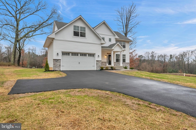 view of front of house featuring board and batten siding, a front lawn, stone siding, and driveway