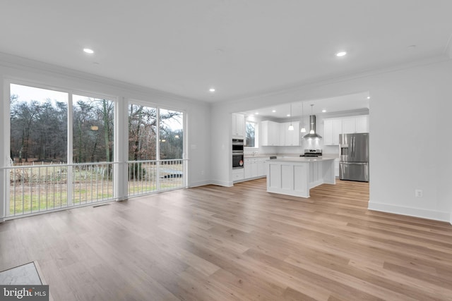 unfurnished living room with light wood-type flooring, a healthy amount of sunlight, and ornamental molding