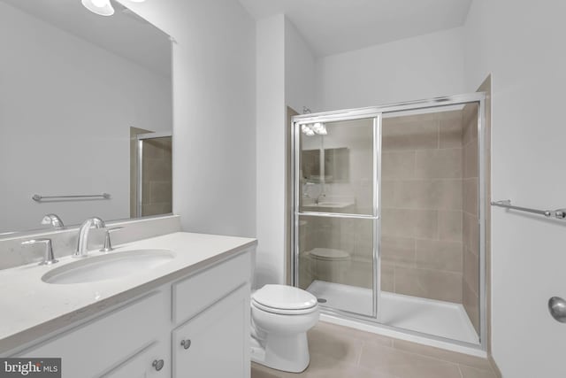 bathroom featuring toilet, a stall shower, vanity, and tile patterned flooring