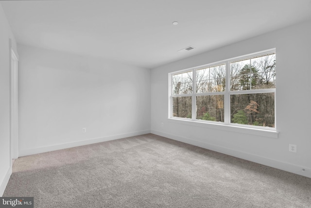 carpeted empty room featuring visible vents and baseboards