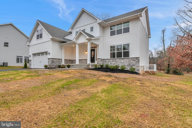 view of front of property featuring a front yard, central air condition unit, a garage, and stone siding