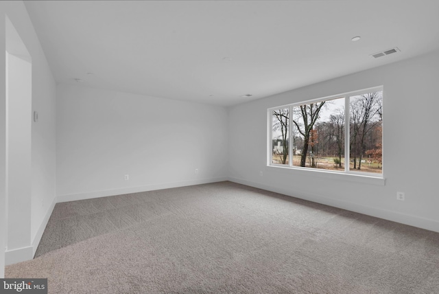 carpeted spare room featuring visible vents and baseboards