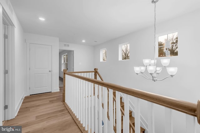 hall featuring visible vents, an upstairs landing, recessed lighting, light wood finished floors, and a chandelier