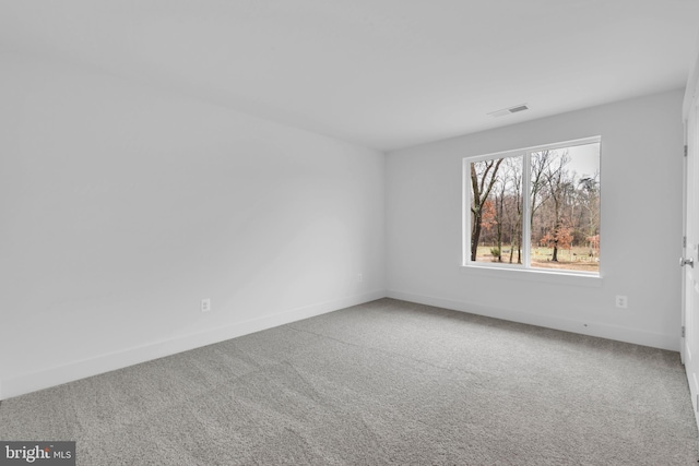 carpeted spare room with visible vents and baseboards