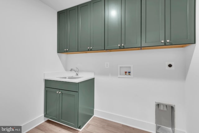 washroom featuring hookup for a washing machine, sink, cabinets, and light hardwood / wood-style floors