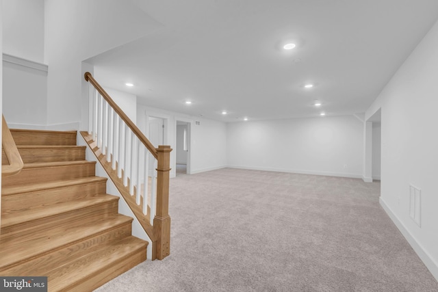 below grade area with stairway, baseboards, visible vents, recessed lighting, and light carpet