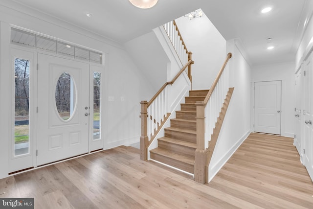 foyer entrance with crown molding and light wood-type flooring