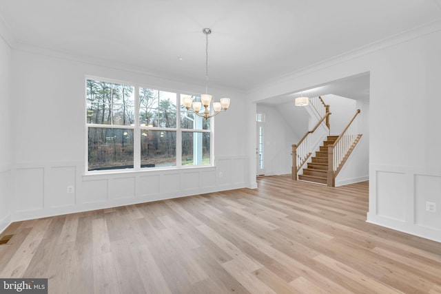 unfurnished dining area featuring light wood-type flooring, stairway, an inviting chandelier, and crown molding