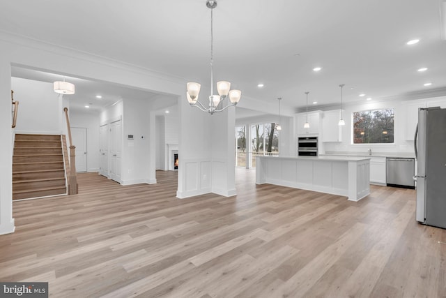 unfurnished living room with light wood finished floors, stairway, a warm lit fireplace, and ornamental molding