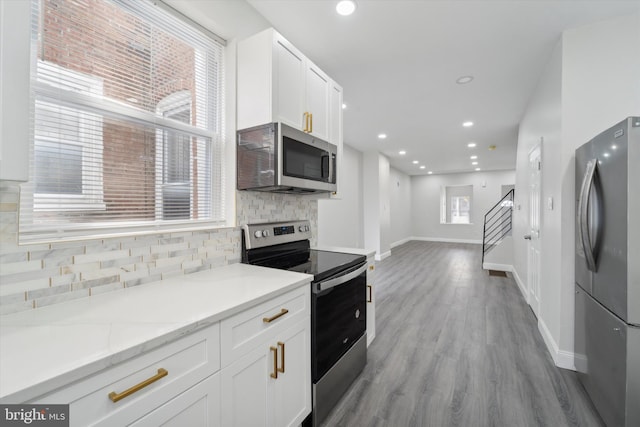 kitchen with a wealth of natural light, appliances with stainless steel finishes, and white cabinets