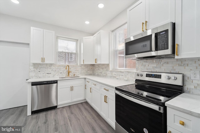 kitchen featuring light wood-type flooring, white cabinets, stainless steel appliances, and sink