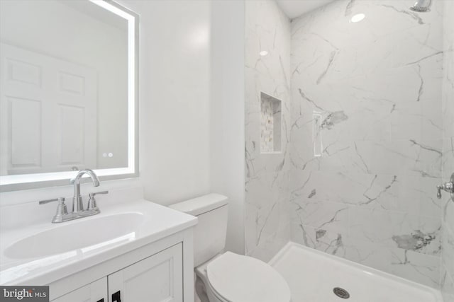 bathroom with vanity, toilet, and tiled shower