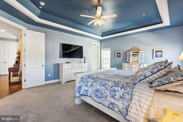 bedroom featuring a tray ceiling, carpet flooring, baseboards, and ceiling fan