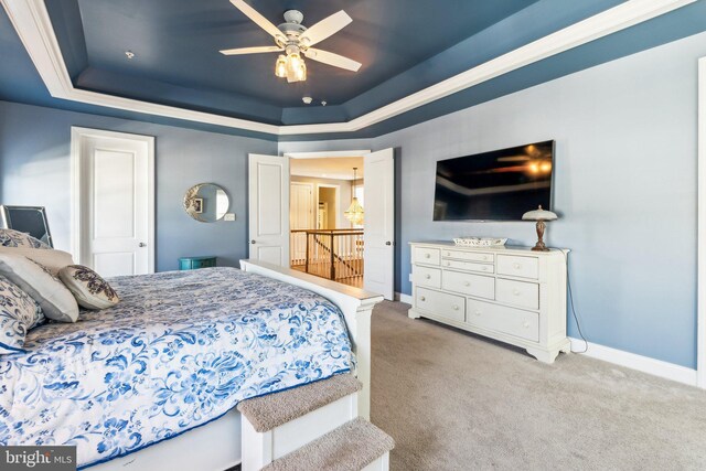 bedroom with a tray ceiling, baseboards, and light colored carpet