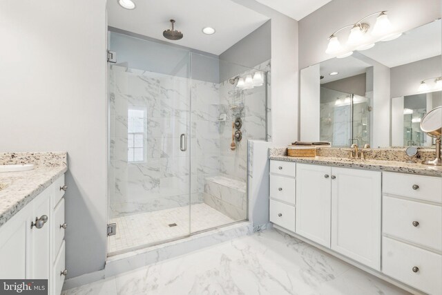 full bathroom featuring a marble finish shower, a sink, marble finish floor, and two vanities